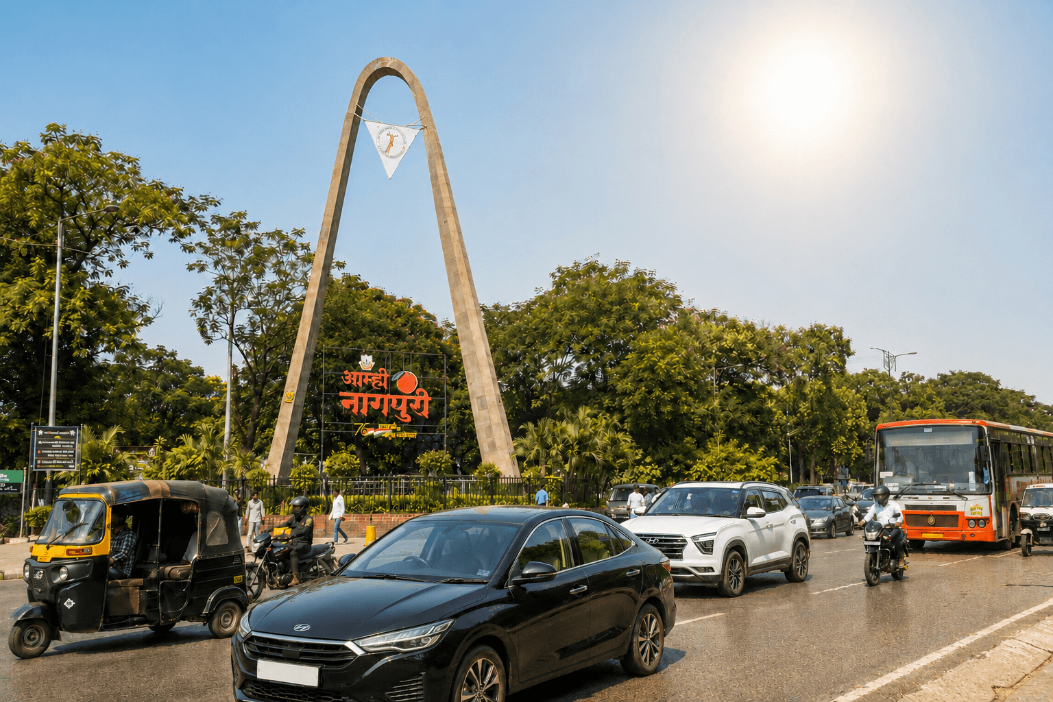 Cars, an auto-rickshaw and a bus in daytime traffic near Nagpur's landmark arch under bright sun